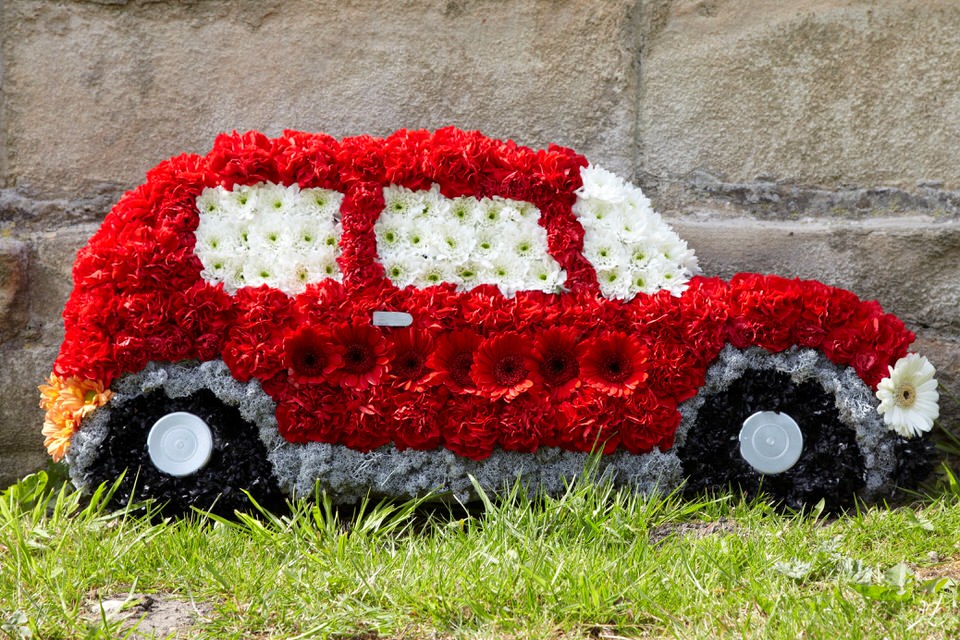 <h2>Red Motor Car Tribute | Funeral Flowers</h2>
<ul>
<li>Approximate Size 80 x 40cm</li>
<li>Hand created red motor car (can be done in other colours)</li>
<li>To give you the best we may occasionally need to make substitutes</li>
<li>Funeral Flowers will be delivered at least 2 hours before the funeral</li>
<li>For delivery area coverage see below</li>
</ul>
<br>
<h2>Liverpool Flower Delivery</h2>
<p>We have a wide selection of Bespoke Funeral Tributes offered for Liverpool Flower Delivery. Bespoke Funeral Tributes can be provided for you in Liverpool, Merseyside and we can organize Funeral flower deliveries for you nationwide. Funeral Flowers can be delivered to the Funeral directors or a house address. They can not be delivered to the crematorium or the church.</p>
<br>
<h2>Flower Delivery Coverage</h2>
<p>Our shop delivers funeral flowers to the following Liverpool postcodes L1 L2 L3 L4 L5 L6 L7 L8 L11 L12 L13 L14 L15 L16 L17 L18 L19 L24 L25 L26 L27 L36 L70 If your order is for an area outside of these we can organise delivery for you through our network of florists. We will ask them to make as close as possible to the image but because of the difference in stock and sundry items it may not be exact.</p>
<br>
<h2>Liverpool Funeral Flowers | Bespoke Tributes</h2>
<p>This motor car funeral design which can be made in any colour (shown here in red) has been loving handcrafted by our expert florists. It features a mass of white spray chrysanthemums, red carnations and red gerberas and features a silver trim and black wheels. It is an ideal tribute for a car enthusiast or classic car owner.</p>
<br>
<p>Bespoke Funeral Tributes are a way to create a tribute that is truly unique and specially designed for a loved one.</p>
<br>
<p>These are sometimes selected by family members as the main tribute or more often a group of friends or workplace colleagues as a symbol of things they associate with the deceased.</p>
<br>
<p>The flowers are arranged in floral foam, which means the flowers have a water source so they look their very best for the day.</p>
<br>
<p>Containing 80 red carnations, 7 white chrysanthemums, 7 red gerberas, 1 white gerbera, 5 tiger chrysanthemums and finished with Finland moss. </p>
<br>
<h2>Best Florist in Liverpool</h2>
<p>Trust Award-winning Liverpool Florist, Booker Flowers and Gifts, to deliver funeral flowers fitting for the occasion delivered in Liverpool, Merseyside and beyond. Our funeral flowers are handcrafted by our team of professional fully qualified who not only lovingly hand make our designs but hand-deliver them, ensuring all our customers are delighted with their flowers. Booker Flowers and Gifts your local Liverpool Flower shop.</p>
<br>
<p><em>Debera G - 5 Star Review on yell.com - Funeral Florist Liverpool</em></p>
<br>
<p><em>Fleur and her team made the flowers for my Dad's funeral. I knew I wanted something quite specific but was quite unsure how to execute the idea. Fleur understood immediately what I was hoping to achieve and developed the ideas into amazingly beautiful flowers that were just perfect. I honestly can't recommend her highly enough - she created something outstanding and unique for my Dad. Thanks Fleur.</em></p>